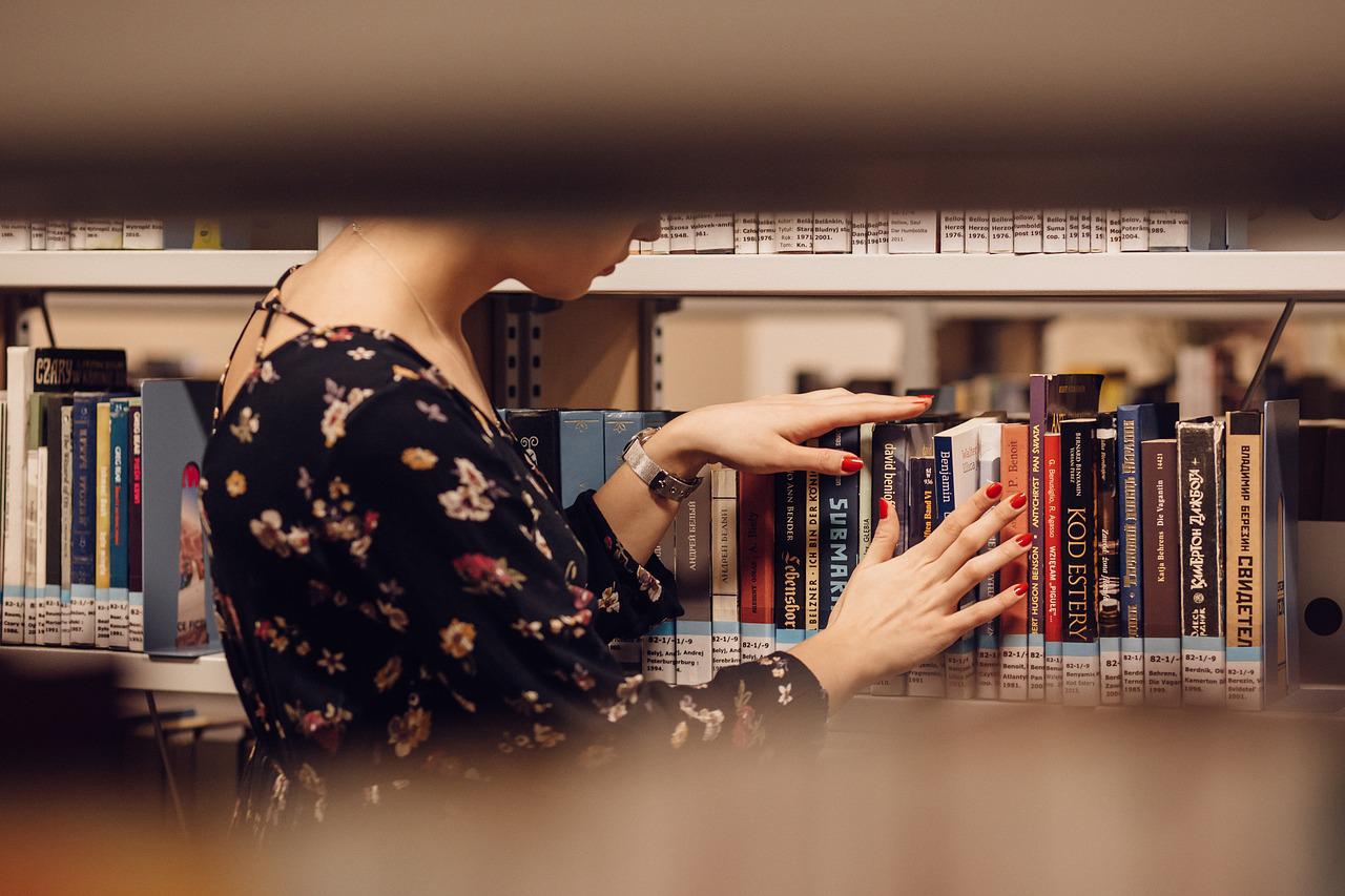 Una lettrice sceglie un libro in biblioteca